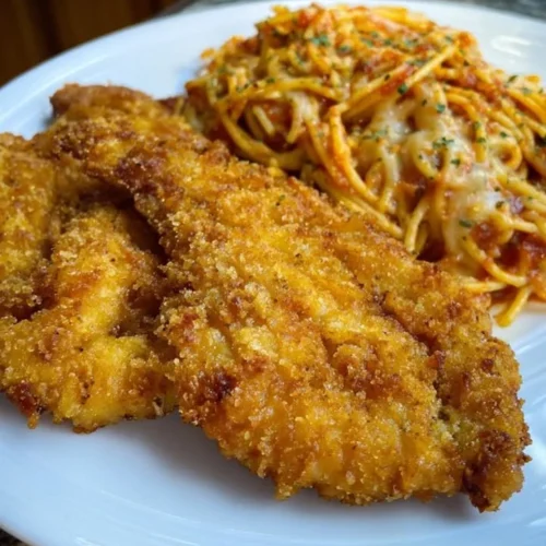 Delicious fried catfish served with spaghetti in a vibrant dish.