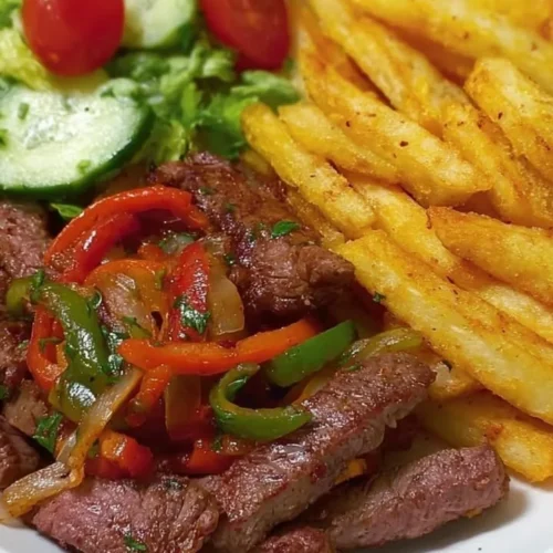 Plate of steak fajitas served with fries and a fresh salad